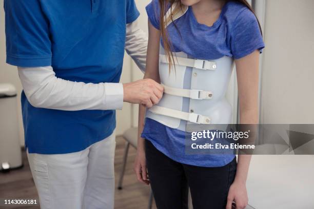 male medical healthcare worker helping a teenager to position a back brace worn for scoliosis correction - skolios bildbanksfoton och bilder