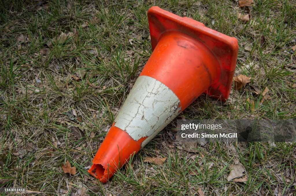 Old traffic cone lying in the grass