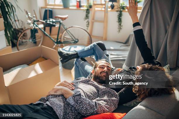 couple relaxing on sofa in new apartment - messy boyfriend stock pictures, royalty-free photos & images