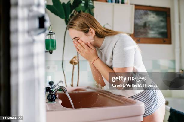 woman in bathroom washing face - washing face stock pictures, royalty-free photos & images