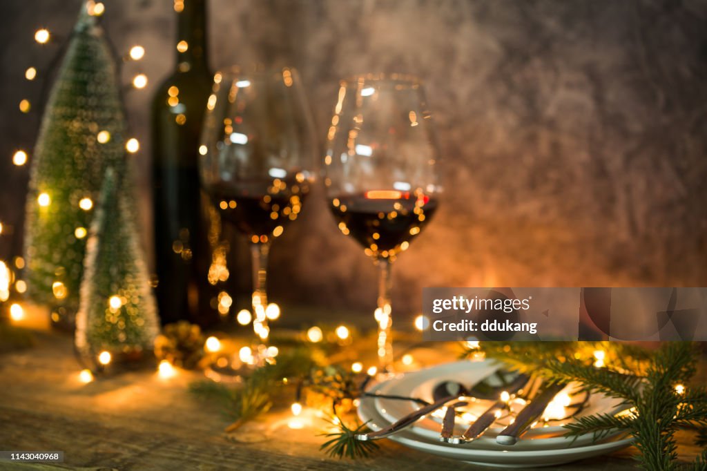 Primo piano di vino rosso in tavola con luci natalizie. Tavola di Natale e albero.