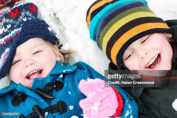 young girl and boy lying in snow - greenwood stock pictures, royalty-free photos & images