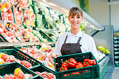 Clerk in a supermarket showing fresh vegetables