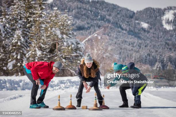 familie beim eisstock schießen am weissensee - winter tourismus - curling for sport stock-fotos und bilder