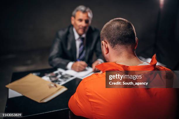 detective interrogating a male prisoner in interrogation room - prosecuting attorney stock pictures, royalty-free photos & images