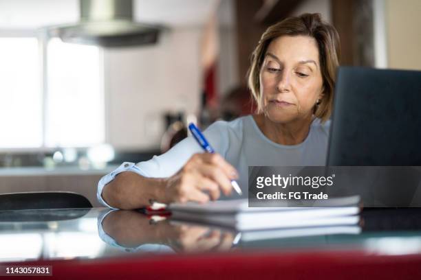 oudere vrouw die thuis werkt - schrijven stockfoto's en -beelden