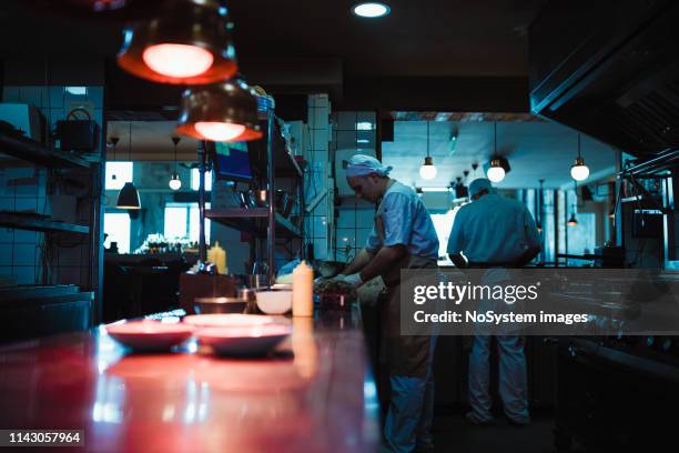 teamwork in the kitchen of the high-end restaurant - dark kitchen stock pictures, royalty-free photos & images