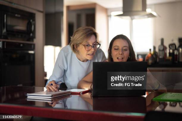 grandmother helping granddaughter with work or homework - granddaughter stock pictures, royalty-free photos & images
