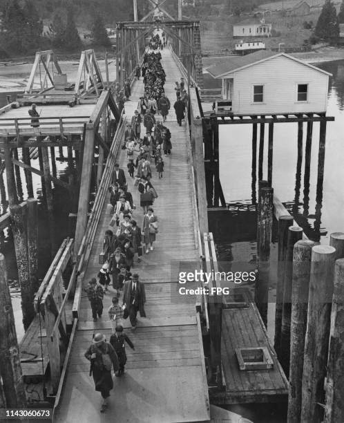 Escorted by armed soldiers, 272 Japanese Americans walk down the Eagledale ferry dock on Bainbridge Island, Washington, to catch the ferry, Kehloken,...