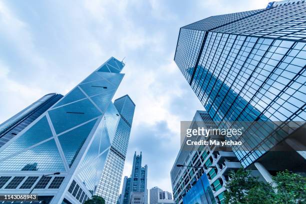 bottom view of modern skyscrapers in business district against blue sky - upper_house stock-fotos und bilder