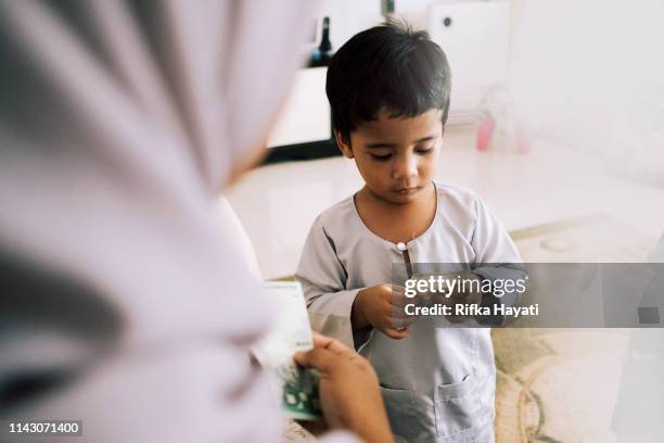 cute kid receiving green packet on eid mubarak - malaysian ringgit stock pictures, royalty-free photos & images