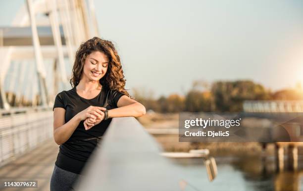 glückliche sportliche junge frau mit einer smarten uhr. - frau uhr stock-fotos und bilder