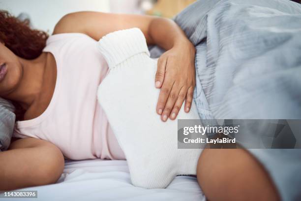 sie versucht alles, um sich vom schmerz zu befreien - wärmflasche stock-fotos und bilder