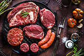 Various cuts of raw meat shot from above on a cast iron grill