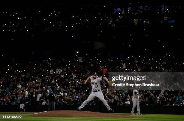 Fans hold up cellphones with lights in stands as relief pitcher Roberto Osuna of the Houston Astros warms up before the ninth inning of game against...