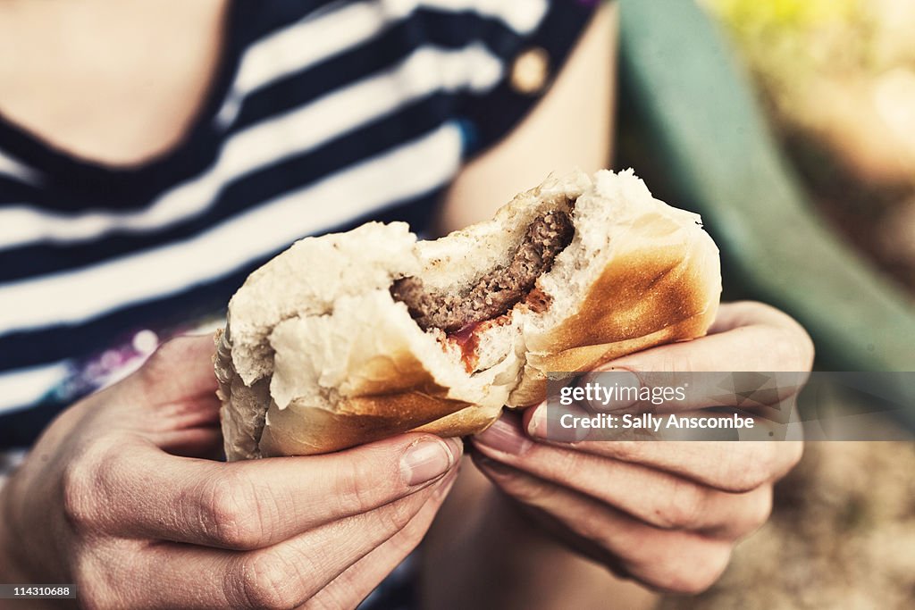 Girl eating a beefburger in a bun