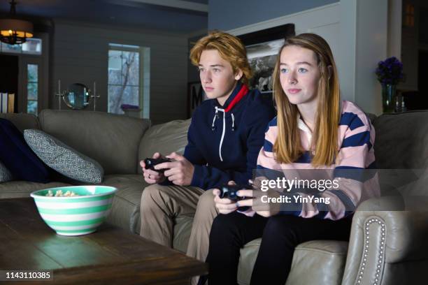 dos adolescentes jugando en frente de la televisión en su casa - concurso tv fotografías e imágenes de stock