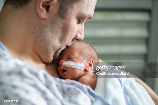 father taking care of his premature baby doing skin to skin at hospital - premature baby stock pictures, royalty-free photos & images