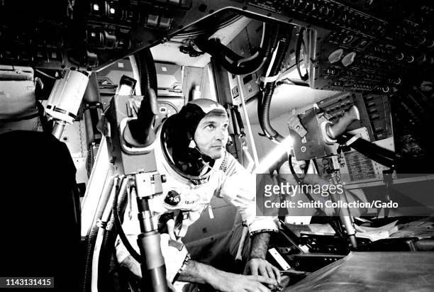 Photograph of the pilot Michael Collins at Apollo 11 Command Module, practicing docking hatch removal from CM simulator at NASA Johnson Space Center,...
