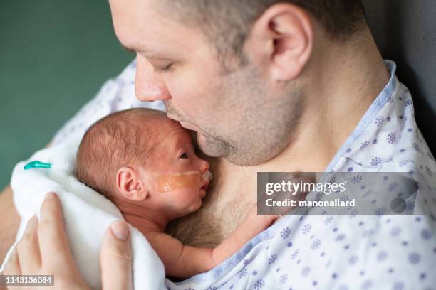 father taking care of his premature baby doing skin to skin at hospital - premature baby stock pictures, royalty-free photos & images