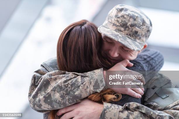 mann umarmt seine frau nach rückkehr aus dem dienst - military spouse stock-fotos und bilder