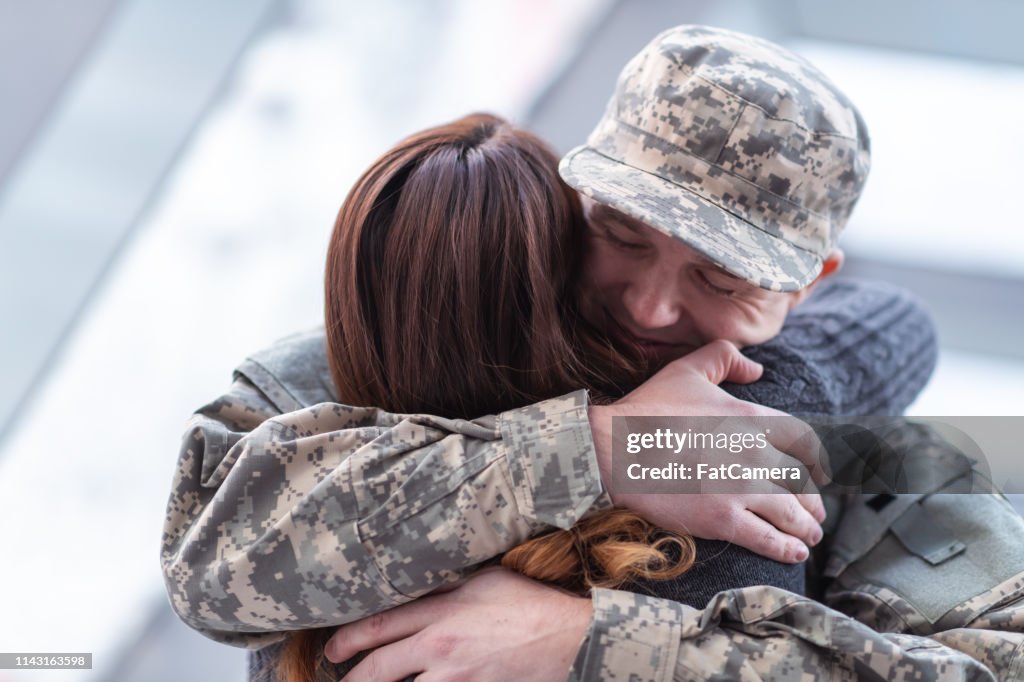 Homem que abraça sua esposa após o retorno para casa do serviço