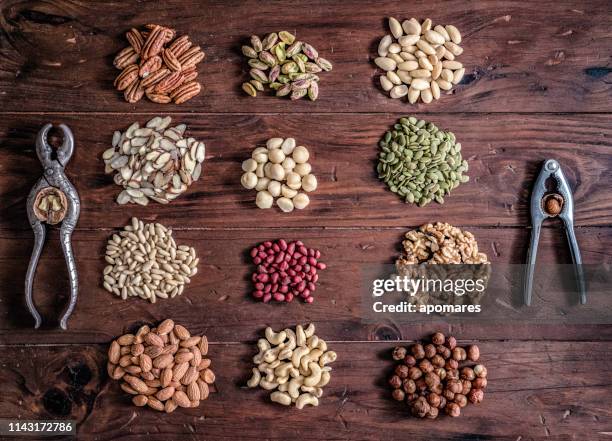 verscheidenheid van gedroogd fruit en noten op een tafel in een ouderwetse rustieke keuken - pijnboompit stockfoto's en -beelden