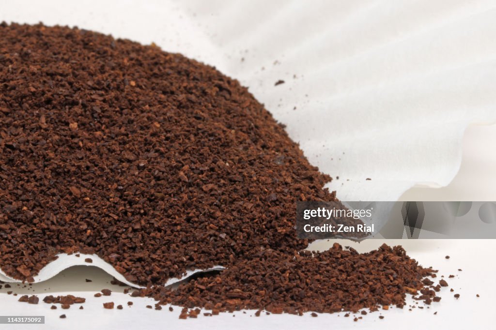 Roasted ground coffee beans poured on paper coffee filter ready for brewing