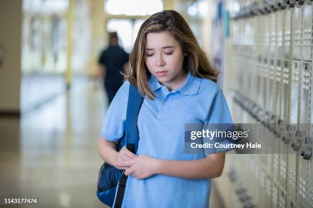 depressed teenage girl standing in hallway - peer pressure stock pictures, royalty-free photos & images