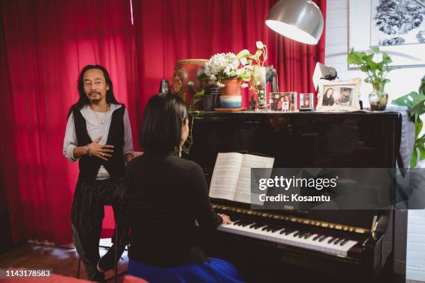 mature man singing while female teacher playing piano - classical musician stock pictures, royalty-free photos & images