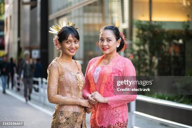 amis dans les vêtements traditionnels souriant pour l’appareil-photo - kebaya photos et images de collection