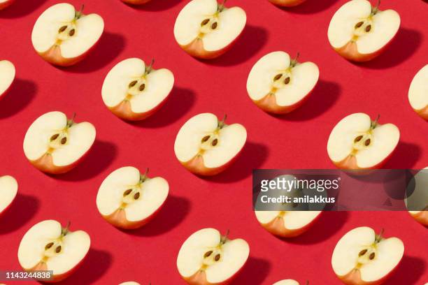 halb geschliffene apples auf rotem hintergrund - apple pattern stock-fotos und bilder