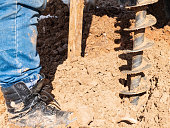 Man drills a geological well. Close up of boot, screw and soil