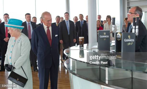 Queen Elizabeth II and Prince Philip, Duke of Edinburgh watch a pint of Guinness being poured as they visit the Guinness Storehouse on May 18, 2011...
