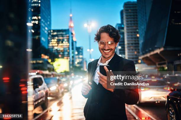 handsome businessman using his smartphone in the city - night suit stock pictures, royalty-free photos & images