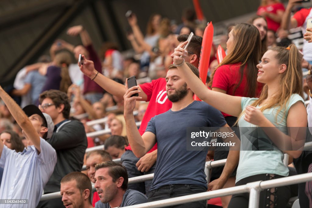 Spectators taking selfie in stadium
