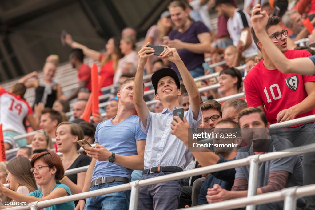 Spectators taking selfie in stadium
