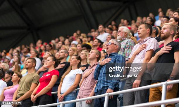 zuschauer singen nationalhymne im stadion - nationalhymne stock-fotos und bilder