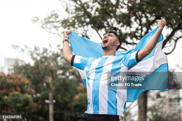 male fan celebrating and holding argentinian flag - argentina soccer imagens e fotografias de stock