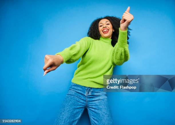 colourful studio portrait of a young woman dancing - glücklichsein stock-fotos und bilder