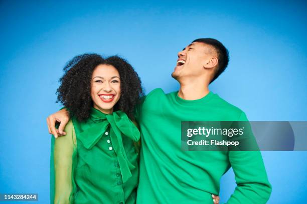 colourful studio portrait of a young woman and man - green and blue background - fotografias e filmes do acervo