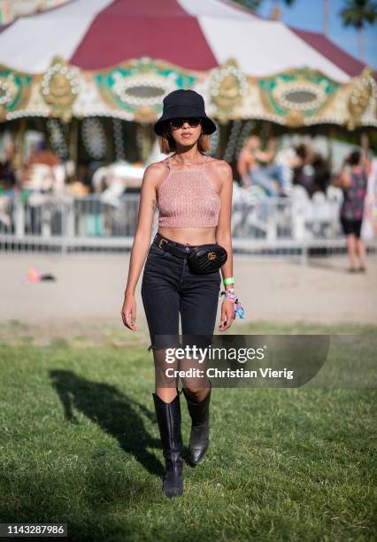 Evelyn Lee is seen wearing cropped top, black denim jeans, bucket hat, cowboy boots at the Revolve Festival during Coachella Festival on April 14,...