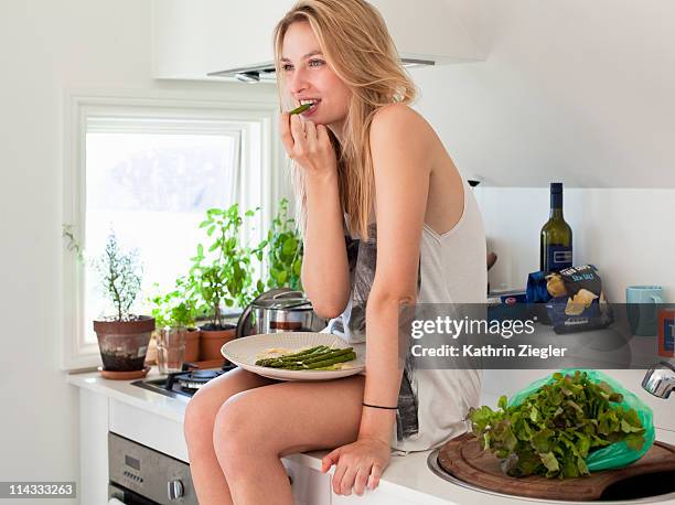 young woman sitting on kitchen counter - young woman healthy eating stock-fotos und bilder