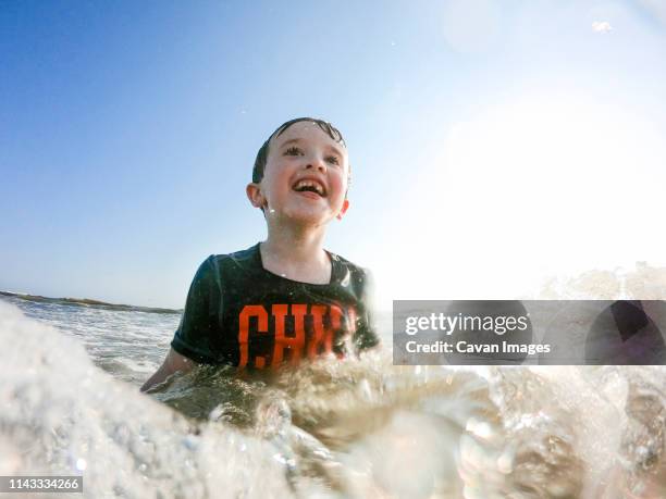 happy boy swimming in sea against sky during sunny day - newport rhode island stock-fotos und bilder