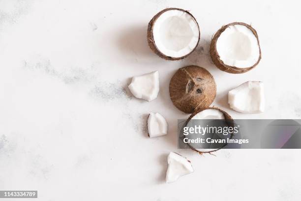 high angle view of coconuts on white table - coco fotografías e imágenes de stock