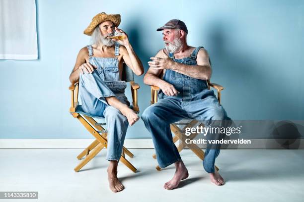 twee hillbillies delen van een biertje - regisseurstoel stockfoto's en -beelden