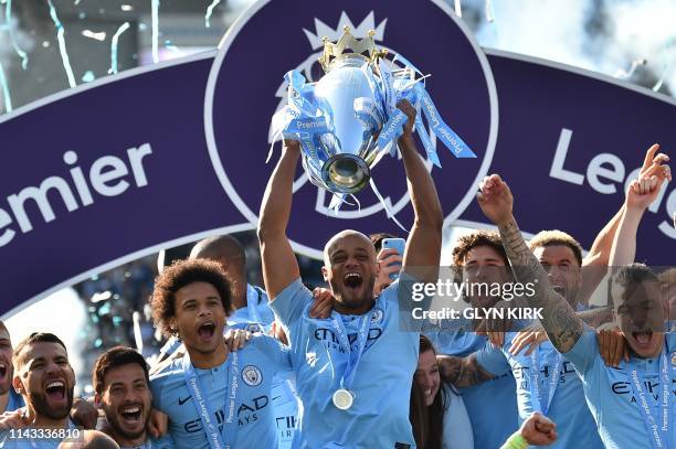 Manchester City's Belgian defender Vincent Kompany holds up the Premier League trophy after their 4-1 victory in the English Premier League football...