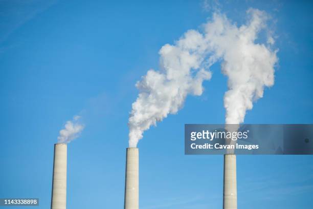 low angle view of smoke emitting from chimneys against clear blue sky - chimney bildbanksfoton och bilder