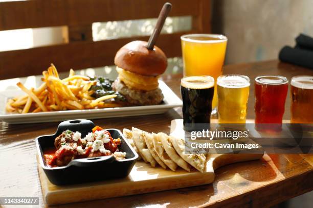 high angle view of fast food with beer served on wooden table in restaurant - beer and food stock pictures, royalty-free photos & images