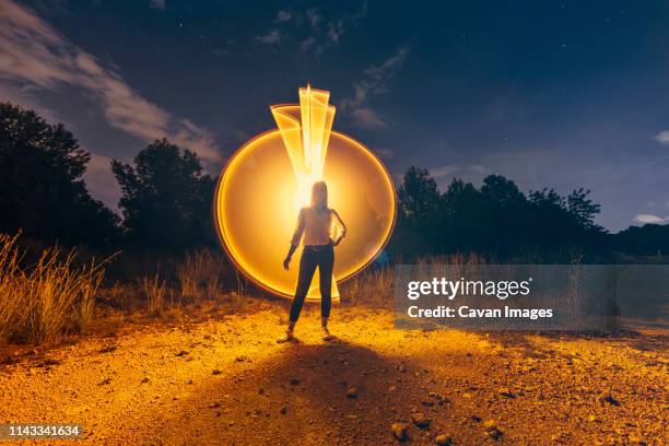 full length of woman standing against light painting on field at night - light painting stock pictures, royalty-free photos & images